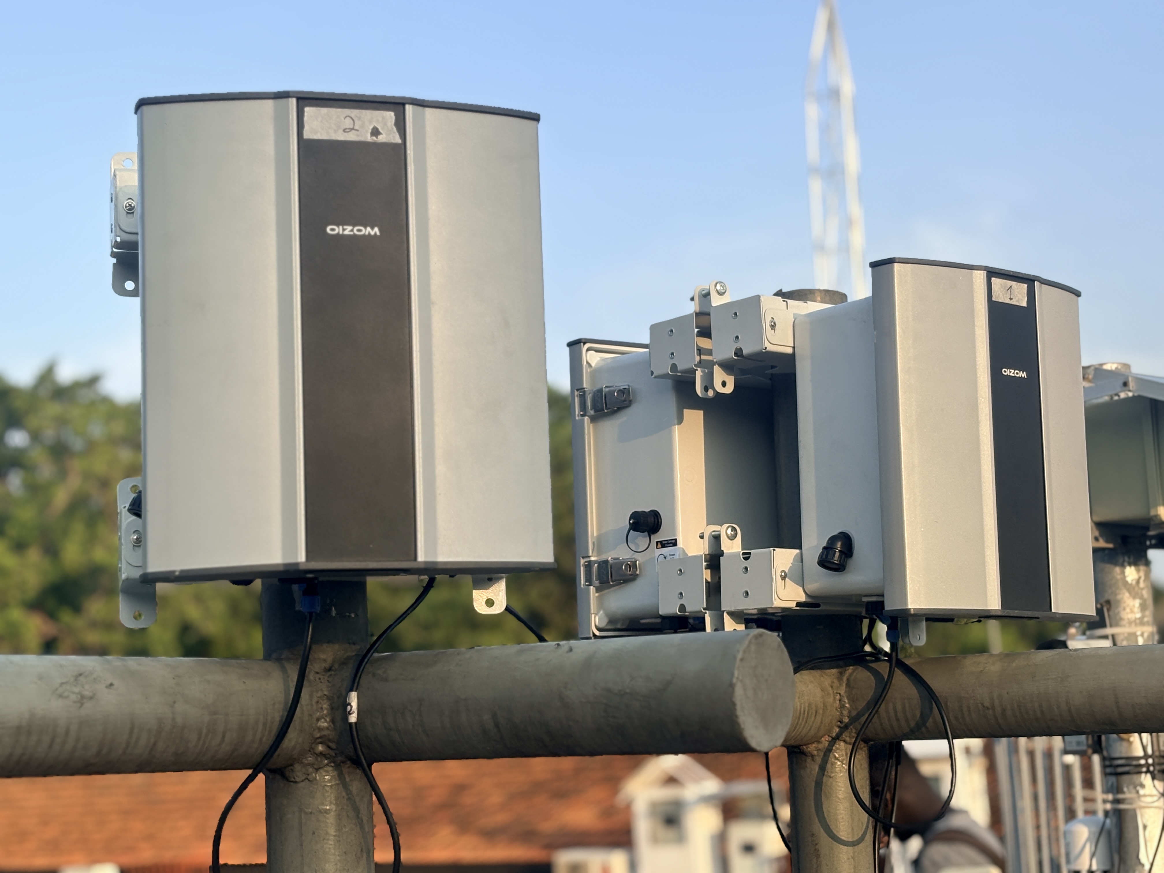 Two Oizom monitors mounted on a site railing